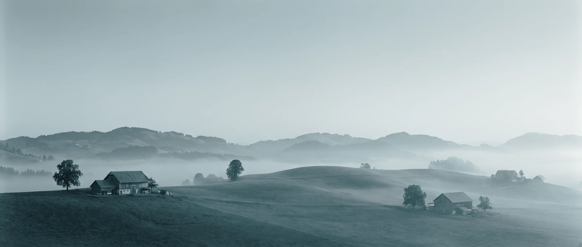 Rolling hills with farmhouses in morning fog